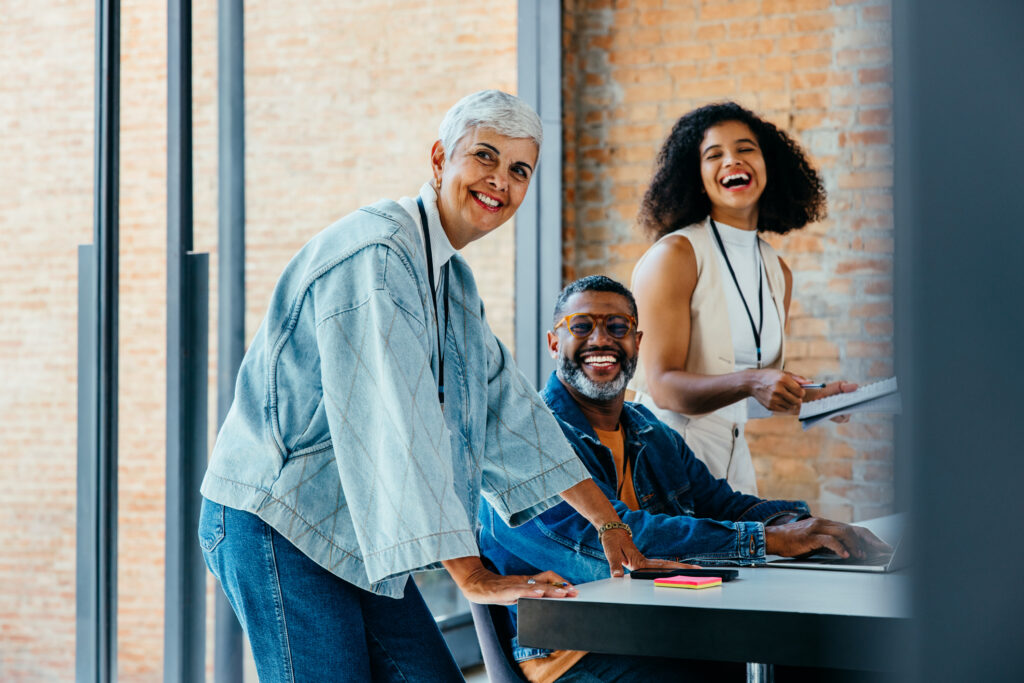 Diverse team of colleagues collaborating and sharing ideas in a bright office space. They are smiling and engaged in a productive meeting.
